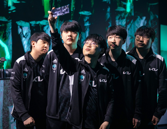 Members of the DWG KIA League of Legends team take a group selfie on the stage of the 2021 Mid-Season Invitational. [RIOT GAMES]