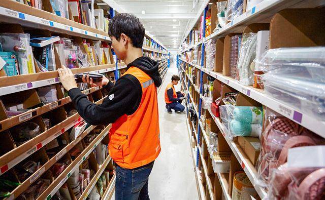 인천 쿠팡 물류센터 직원들이 다양한 제품이 뒤섞여 있는 선반에서 고객에게 배송할 제품을 골라내고 있다. 쿠팡 제공