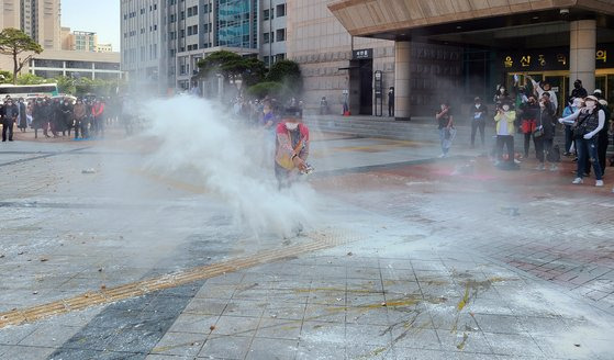 지난달 24일 오후 울산시청 앞에서 열린 유흥업소 업주들의 집회에서 한 참석자가 밀가루를 뿌리고 있다. 업주들은 울산시에 집합 금지 중단과 휴업에 따른 보상을 요구했다. 연합뉴스