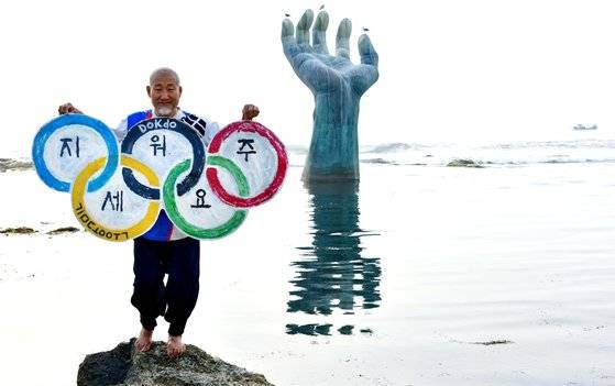 현충일을 앞둔 2일 경북 포항 남구 호미곶 손 조형물 앞에서 서예가 김동욱씨가 일본 지도에 독도를 삭제하라는 퍼포먼스를 하고 있다. 연합뉴스(서예가 김동욱씨 제공)