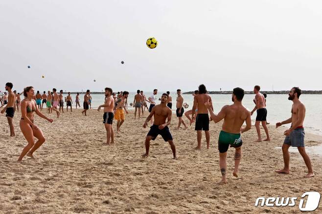 지난 4월19일(현지시간) 야외 마스크 착용 의무화 해제로 이스라엘 텔아비브 해변에서 시민들이 ‘노 마스크’로 공놀이를 하고 있다. © AFP=뉴스1 © News1 우동명 기자