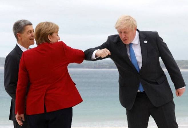 앙겔라 메르켈 독일 총리(가운데)가 G7 정상회의 의장인 보리스 존슨 영국 총리(오른쪽)과 팔꿈치 인사를 나누는 모습을 남편 요아힘 자우어 교수가 웃으며 지켜보고 있다. 콘월=AFP연합뉴스