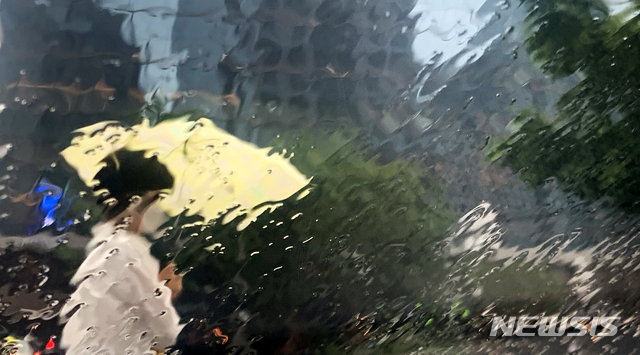 [서울=뉴시스]조수정 기자 = 전국적으로 비가 내리고 있는 지난 18일 오전 서울 중구 세종대로에서 시민들이 우산을 들고 걸어가는 모습이 빗물이 흘러내리는 유리창에 투영되고 있다. 2021.06.18. chocrystal@newsis.com