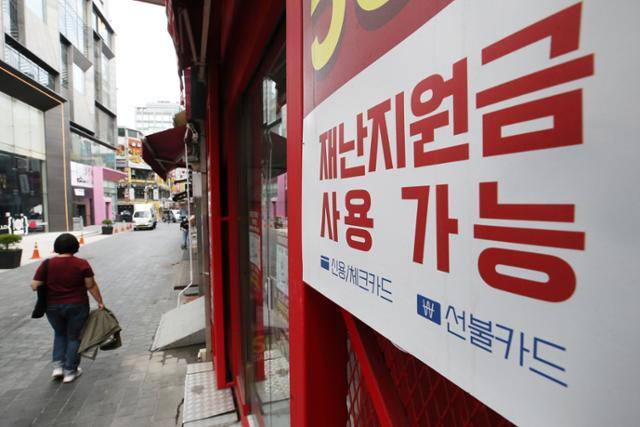 더불어민주당이 재난지원금 전 국민 지급 원칙을 재확인한 22일 오전 서울 중구 명동의 한 점포에 재난지원금 사용이 가능함을 알리는 안내문이 부착돼 있다. 뉴스1