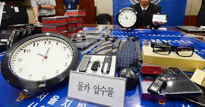 다양한 ‘몰카’ 장비들 - 사진은 과거에 서울 서대문구 미근동 경찰청에서 한 경찰관이 벽걸이 시계형, 안경형, 넥타이형 등 밀수입된 각종 미인증 불법 몰래카메라 압수품들을 공개하고 있는 모습. 손형준 기자 boltagoo@seoul.co.kr