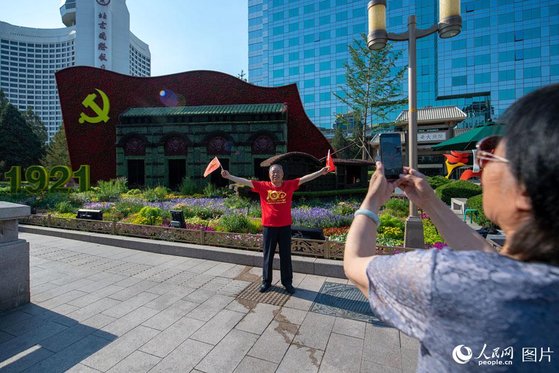 중국 베이징의 시민들이 중공 창당 100주년을 축하하기 위해 조성된 화단을 배경으로 사진을 찍고 있다. [중국인민망 캡처]