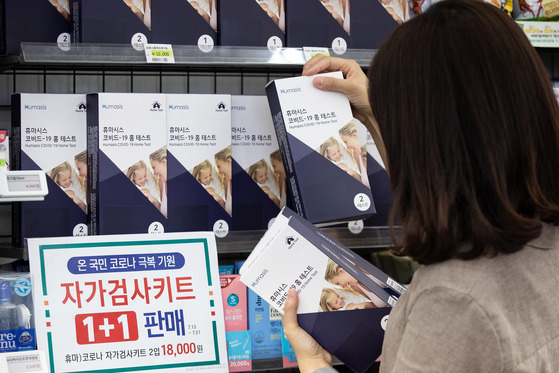 A customer looks through coronavirus self-test kits at a convenience store in Seoul on Wednesday. Convenience store franchise 7-Eleven is running a buy one, get one free promotion on self-test kits through July 31 as daily infection cases in Korea continue to hit new highs. [NEWS1]