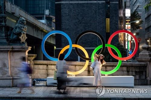 일본 도쿄도(東京都) 주오구(中央區)에 설치된 오륜 조형물을 배경으로 한 여성이 기념 사진을 찍고 있다. [도쿄 AFP=연합뉴스]