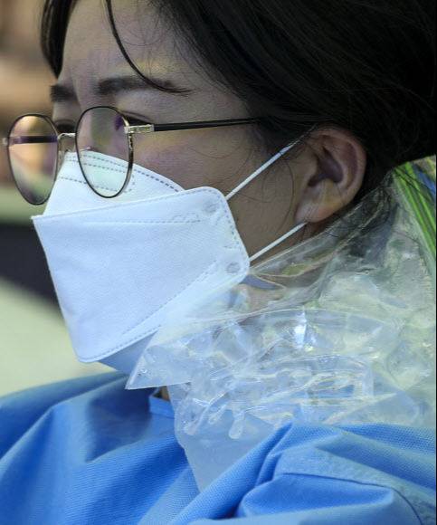 폭염이 이어지고 있는 15일 오후 서울 양천구 파리공원에 설치된 찾아가는 선별진료소에서 의료진이 아이스팩을 어깨에 대고 있다. 뉴시스