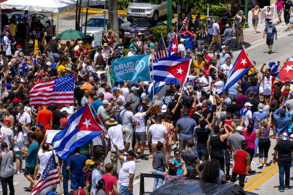 쿠바에서 반정부 시위가 열린 11일(현지시간) 미국 플로리다주 마이애미의 쿠바인 거주지 리틀 아바나의 시민들이 쿠바기와 미국 성조기를 나눠 들고 연대 시위에 나서고 있다.마이애미 AP 연합뉴스
