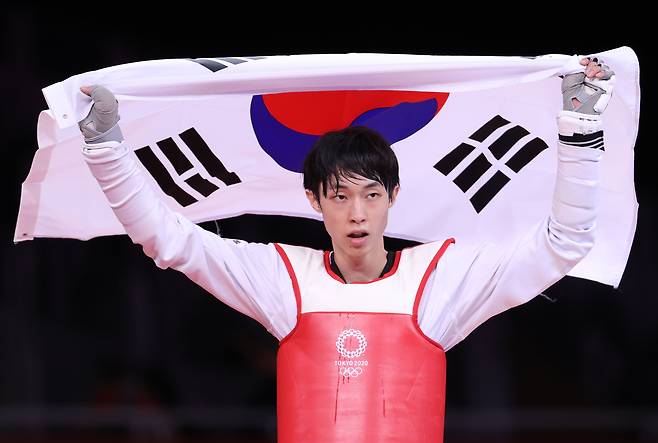 24일 일본 마쿠하리 메세 A홀에서 열린 도쿄올림픽 남자 태권도 58㎏급 경기에서 동메달을 획득한 장준이 태극기를 들고 세리머니를 하고 있다. /연합뉴스