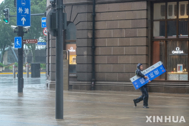 [상하이=신화/뉴시스] 25일 중국 상하이에서 한 직원이 제6호 태풍 인파 영향으로 강풍에 쓰러진 안내판을 들고 이동하고 있다. 2021.07.27.