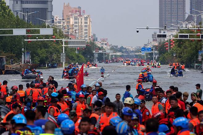 중국 중부 허난성 신샹시 웨이후이에서 26일(현지시간) 구조대가 홍수로 고립된 주민들을 구조용 고무보트에 태워 안전지대로 대피시키고 있다. 허난성에서는 최근 내린 기록적인 폭우로 63명이 숨지고 5명이 실종됐다. /연합뉴스