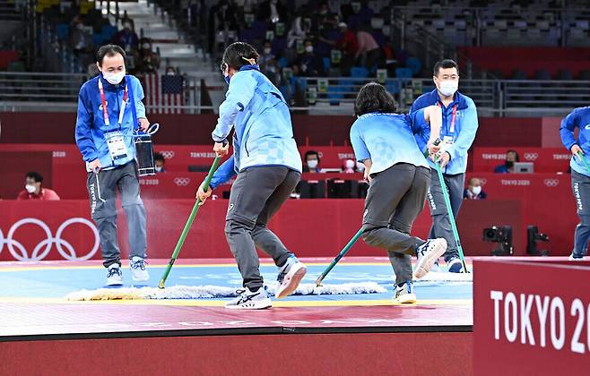 Volunteers for the Tokyo Olympics sanitize the venue during a taekwondo event on Tuesday. (pool photo)