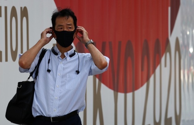 마스크를 쓴 남성이 도쿄올림픽 안내판 앞을 지나고 있다. 사진=REUTERS