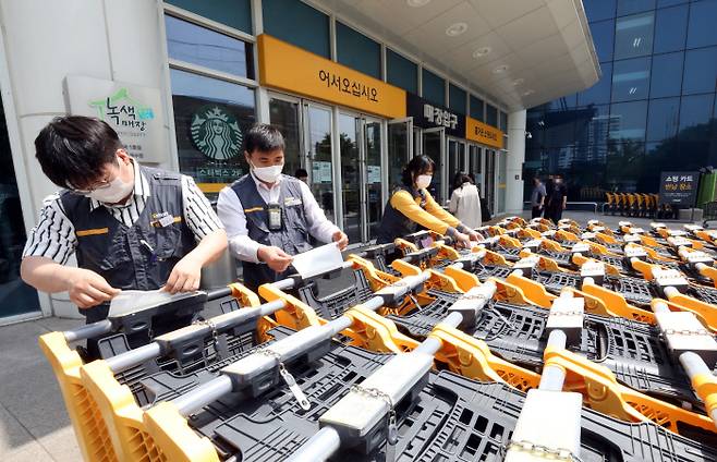 이마트 서울 성수점 직원들이 영업 시작 전 카트 손잡이에 항균 필름을 붙이고 있다.