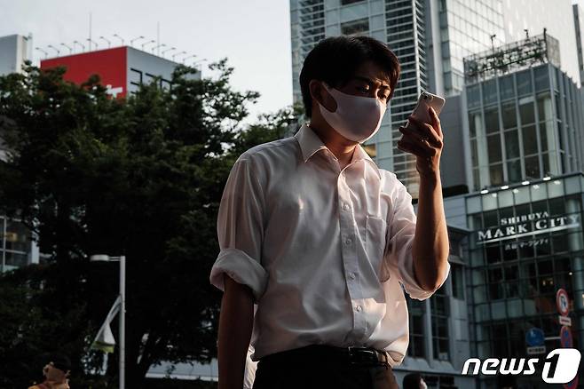 28일 도쿄도에서 마스크를 쓴 행인이 스마트폰을 보며 거리를 걷고 있다. © AFP=뉴스1