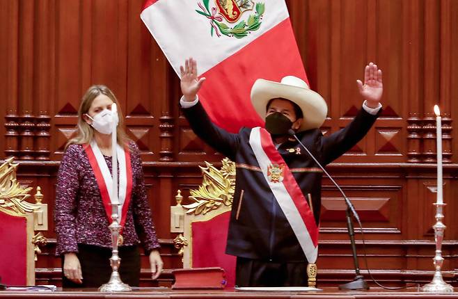 28일 페루 리마 국회의사당에서 열린 신임 대통령 취임식에서 페트로 카스티요 대통령이 마리아 델 카르멘 알바 국회의장이 대통령 현장(어깨에서 허리로 늘어뜨리는 띠)을 걸어준 뒤 두 손을 들고 있다. AFP=연합뉴스