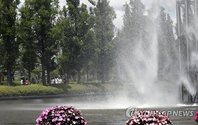 시원하게 쏟아지는 인공폭포 연일 불볕더위가 이어지는 가운데 지난 20일 오후 부산시민공원 하늘빛 폭포를 찾은 시민들이 시원하게 쏟아지는 물줄기 아래를 지나고 있다. [연합뉴스 자료사진]