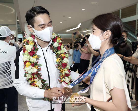 2020도쿄올림픽을 마친 펜싱 남자 사브르 대표팀이 29일 오후 인천국제공항을 통해 입국했다. 대표팀 김정환이 입국장에 도착해 마중나온 아내에게 금메달과 동메달을 걸어주고 환하게 웃고 있다. 인천공항=김민규 기자