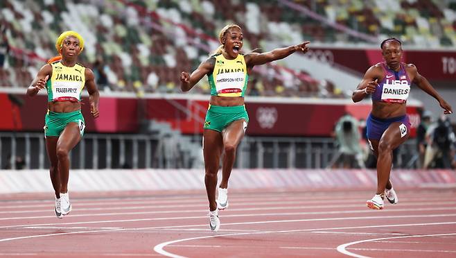 자메이카의 일레인 톰프슨(가운데)이 31일 도쿄 올림픽 스타디움에서 열린 2020 도쿄올림픽 육상 여자 100ｍ 결선에서 1위로 결승선에 들어오며 환호하고 있다. 도쿄=EPA연합뉴스