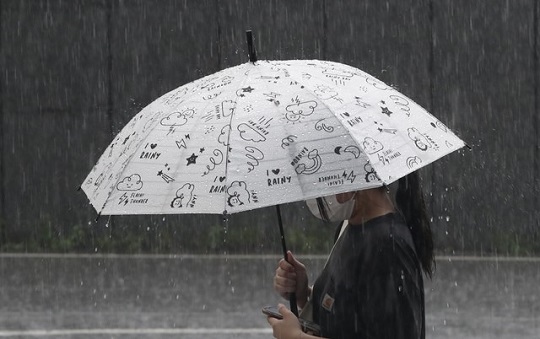 지난달 19일 서울 중구의 한 대형 빌딩 앞에서 우산을 쓴 시민이 발걸음을 재촉하고 있다. 사진=뉴시스