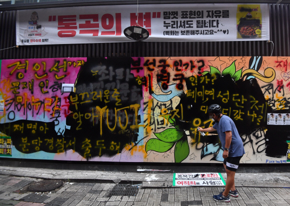 1일 서울 종로의 한 서점 담벼락에그려진 쥴리벽화에 한 시민이 자신의 의견을 담은 메시지를 덧칠하고 있다. 2021.8.1 박지환기자 popocar@seoul.co.kr