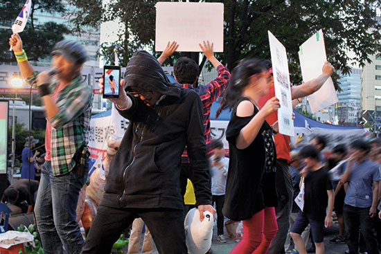 2014년 9월13일 ‘세월호 특별법 반대 집회’에서 한 참가자가 여성의 나체 사진을 스마트폰에 띄운 채 춤을 추고 있다. 그가 들고 있는 인형은 일베 마스코트 ‘베츙’이다. ⓒ시사IN 김동인