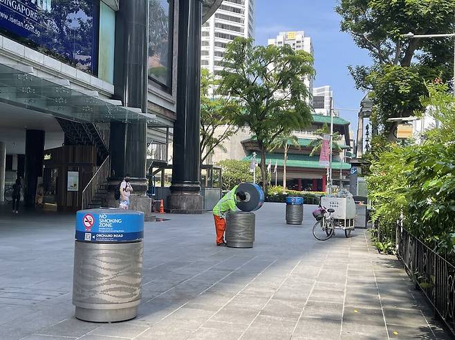 2021년 7월14일 싱가포르의 한 건물 앞에 줄줄이 놓인 쓰레기통을 이주노동자가 치우고 있다.