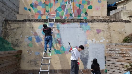 벽화 화가로 나서 구슬땀을 흘리고 있는 동명대 학생들.
