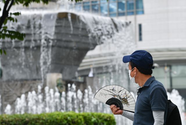 2일 서울 중구 명동에서 한 시민이 부채질을 하며 분수대를 바라보고 있다. 이날 서울에서는 흐리고 비가 내리는 가운데 낮 최고기온 30도에 달하는 무더위가 이어졌다. 이한결 기자