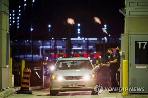 서류를 받는 캐나다 국경관리청(CBSA) 직원  (로이터=연합뉴스) 9일(현지시간) 캐나다 온타리오주 국경에서 캐나다 국경관리청(CBSA) 직원이 입국자에게 서류를 받고 있다.