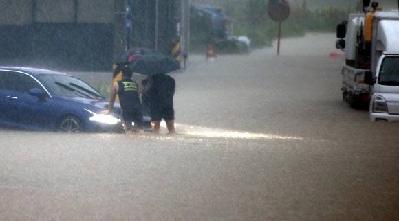 침수 차량 꺼내는 젊은이들 - 호우 경보가 내려지면서 게릴라성 집중호우가 쏟아진 18일 새벽 강원 강릉 시내에서 젊은이들이 물에 잠겨 멈춰 선 다른 사람의 차량을 밀어주고 있다. 이 차는 결국 견인차로 끌어냈다. 2021.8.18 연합뉴스