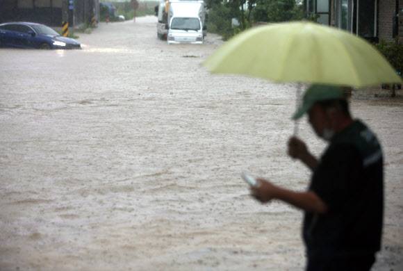 저 차를 어떻게 꺼내지 - 호우 경보가 내려지면서 게릴라성 집중호우가 쏟아진 18일 새벽 강원 강릉 시내에서 견인업체 직원이 물에 잠겨 멈춰 선 차량을 구조하기 위해 고심하고 있다. 2021.8.18 연합뉴스