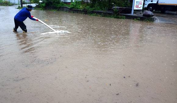 “배수구를 찾아라” - 호우 경보가 내려지면서 게릴라성 집중호우가 쏟아진 18일 강원 강릉 시내에서 한 시민이 물에 잠긴 도로에서 배수구를 찾고 있다. 2021.8.18 연합뉴스