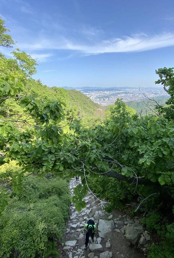 지난 5월 12일 북한산 하루재에서 바라본 서울 강북구 우이동 방향. 한 등산객이 고개를 숙여 하루재 고갯마루를 향해 힘을 자아내고 있다. 김홍준 기자