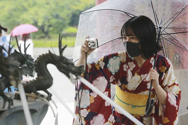 일본 도쿄 아사쿠사 인근에서 기모노와 마스크를 착용한 한 여성이 사진을 찍고 있다. AP/뉴시스