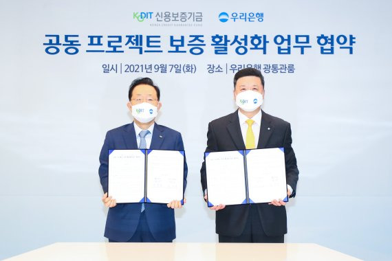 권광석 우리은행장(오른쪽)과 윤대희 신용보증기금 이사장이 7일 서울 소공로 우리은행 본점에서 '공동 프로젝트 보증 활성화를 위한 업무협약'을 체결한 뒤 협약서를 들어보이고 있다.