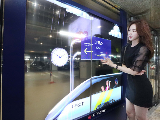 모델이 서울 강남구 코엑스 주차장 출입구에 설치된 LG디스플레이 투명 OLED를 보고 있다. <LG디스플레이 제공>