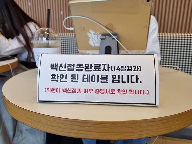 11일 오후 서울 서초구 한 카페 좌석 위에 ‘코로나 백신 접종을 마친 사람이 앉는 테이블’이라고 알려주는 안내판이 놓여 있다. /강다은 기자