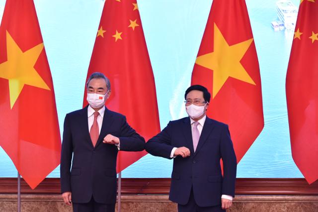 왕이(왼쪽) 중국 외교부장이 10일 베트남 하노이를 방문해 팜 빈 민 베트남 부총리와 팔꿈치 인사를 하고 있다. 하노이=연합뉴스