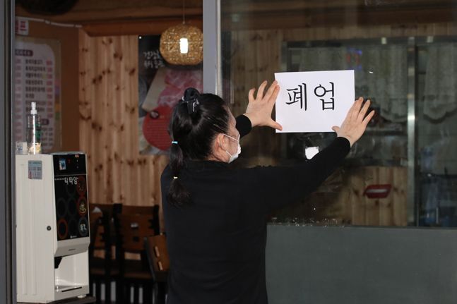서울에서 한 식당주인이 식당 문에 폐업이 적힌 종이를 붙이고 있다.ⓒ데일리안