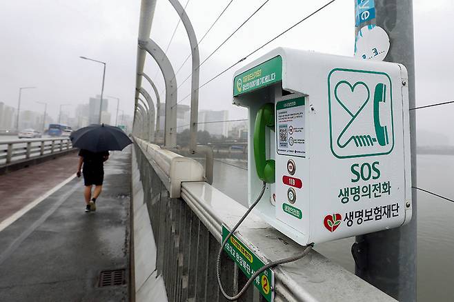 지난 7월 서울 마포대교에서 자살 예방을 위해 설치된 '생명의 전화'를 한 시민이 지나는 모습. /사진=뉴스1 DB