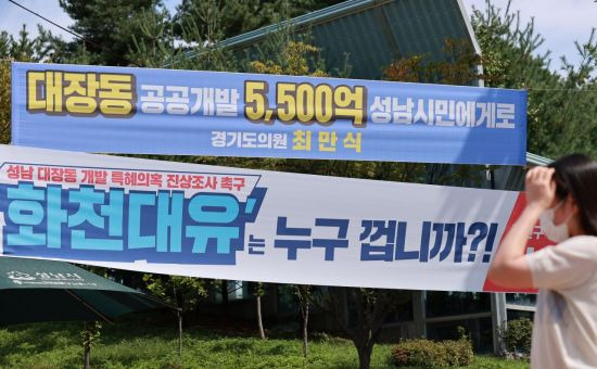 24일 경기도 성남시청 인근 교차로에 성남 대장동 개발 사업과 관련해 더불어민주당 소속 경기도의회 의원과 국민의힘 지역 당협위원장 이름으로 상반된 의미의 현수막이 나란히 걸려 있다.