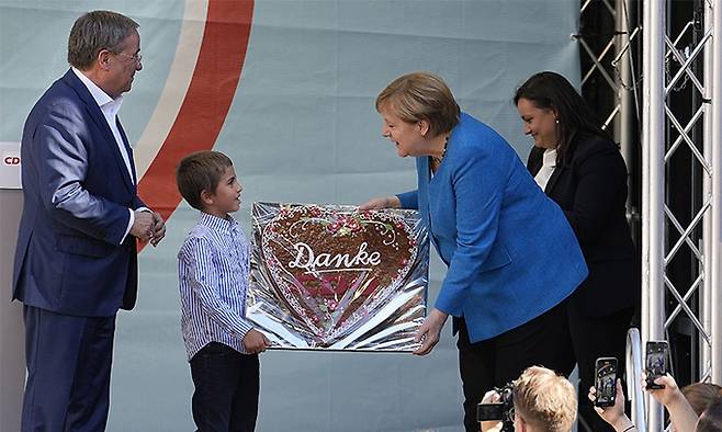 독일 총선을 하루 앞둔 지난 25일(현지시간) 기독민주당(CDU)·기독사회당(CSU) 연합 총리 후보인 아르민 라셰트(왼쪽)의 지역구 아헨에서 지원 유세에 나선 앙겔라 메르켈(오른쪽) 총리가 한 어린이로부터 전통 쿠키를 선물 받고 있다. 아헨=EPA연합뉴스