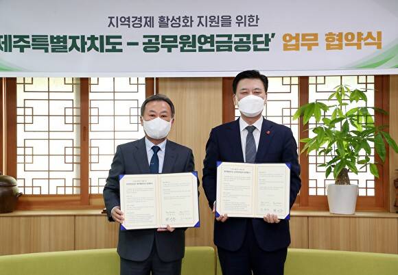 이달 27일 구만섭 제주특별자치도지사 권한대행(오른쪽)과 황서종 공무원연금공단 이사장이 제주도청 소통회의실에서 공무원연금공단과 ‘지역경제 활성화 지원을 위한 업무협약’을 체결하고 있다. [사진=제주도청 ]