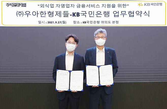 지난 27일 KB국민은행 여의도 본점에서 열린 외식업 자영업자 금융서비스 지원을 위한 KB국민은행·우아한형제들 업무 협약식에서 허인(오른쪽) KB국민은행장과 김범준 우아한형제들 대표이사가 업무협약을 체결하고 기념촬영을 하고 있다./사진=KB국민은행