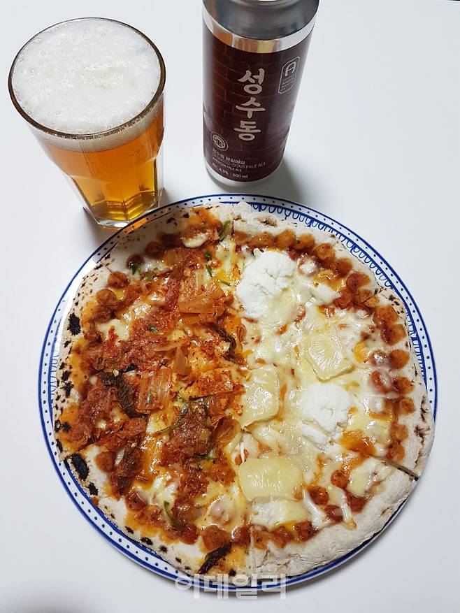 양유 냉동 화덕피자 브랜드 ‘우주인피자’의 ‘파이브치즈’와 ‘김치피자’를 집에서 반반피자로 즐겨봤다. 수제맥주 어메이징브루잉컴퍼니 ‘성수동 페일에일’ 캔맥주와 함께.(사진=김범준 기자)