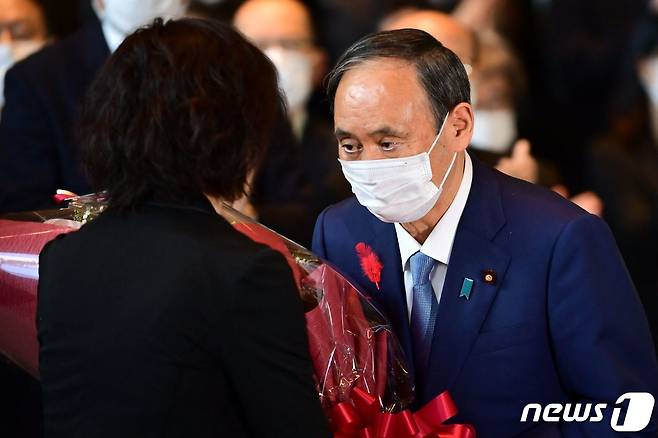 스가 요시히데 일본 총리가 4일 도쿄에서 마지막 각의를 주재한 뒤 참모들로부터 꽃다발을 받았다. © AFP=뉴스1 © AFP=뉴스1