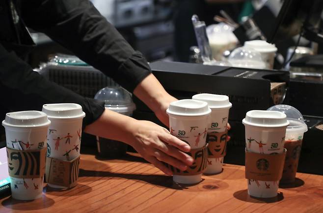 A Starbucks employee serves drinks in reusable plastic cups made as part of the coffee chain's 50th anniversary on Sept. 28th. (Yonhap)